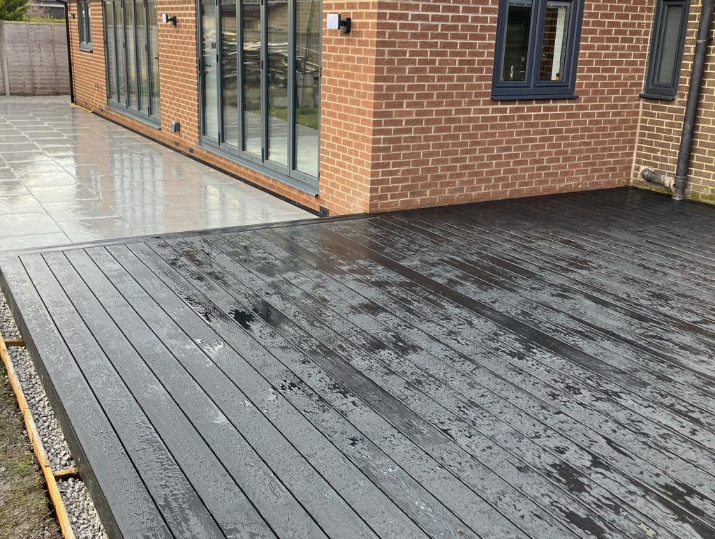 Completed composite deck and paved area beside a house