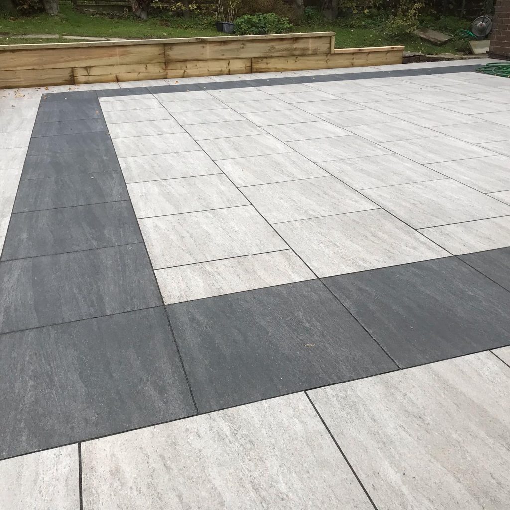 Porcelain patio arranged with contrasting dark paving to create a geometric border pattern